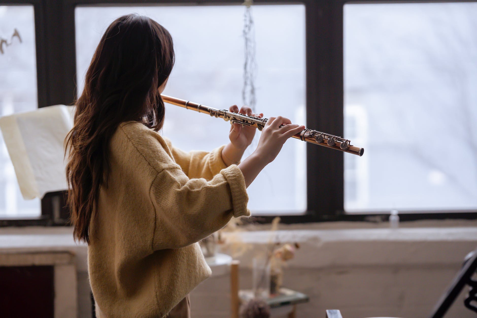 faceless woman playing flute next to window in studio