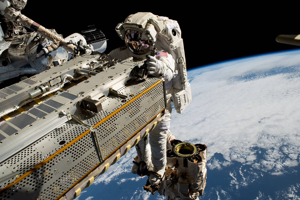 The Big Picture: Astronaut rides a robotic arm in space.
