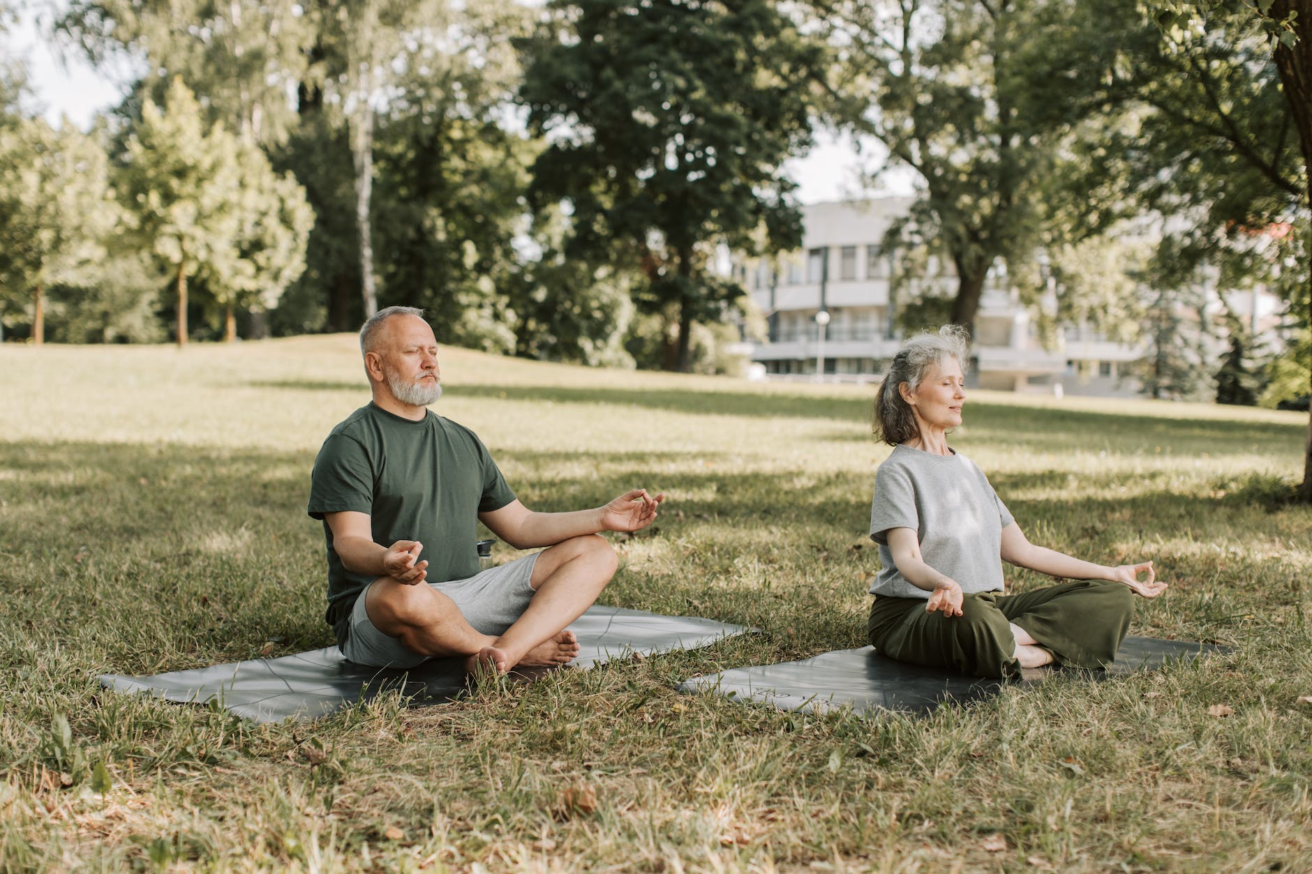 an elderly couple meditating at the park